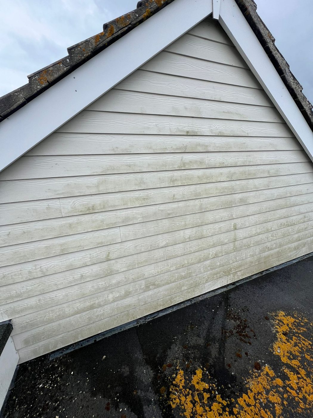 Cleaning algae from the bargeboards and cladding at a roof apex