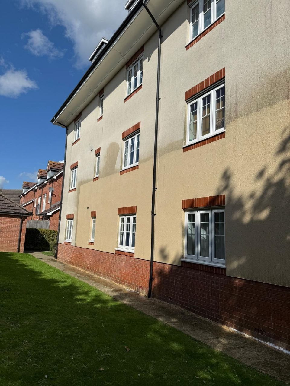 Render on an apartment block stained with algae before soft washing