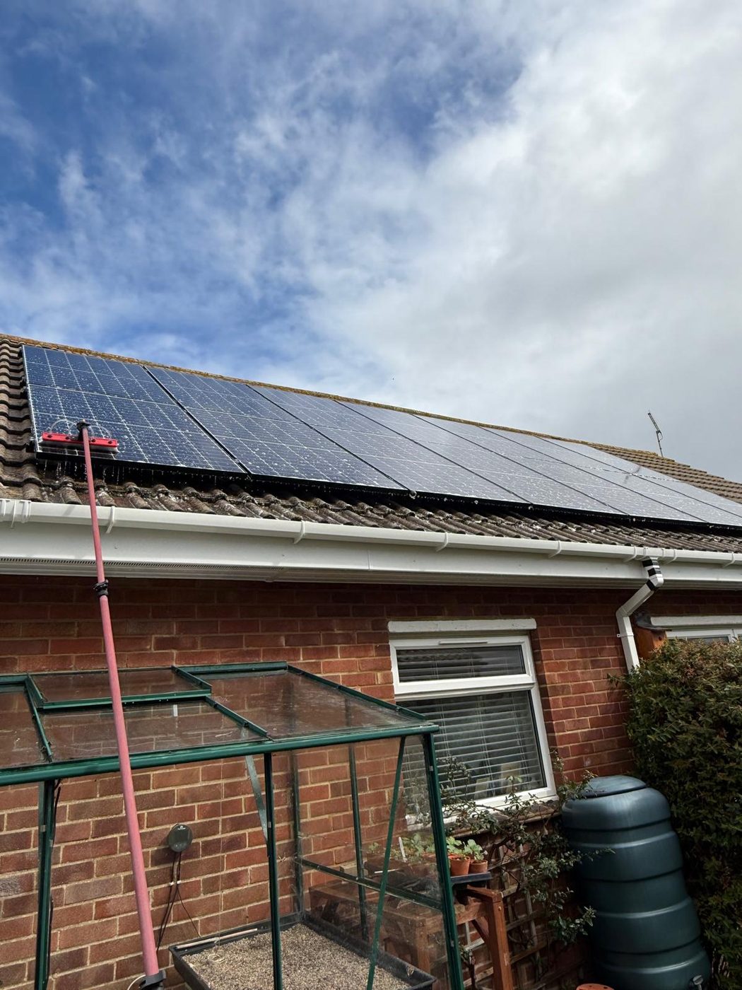 Cleaning a domestic rooftop solar panel array in West Sussex with a reach pole