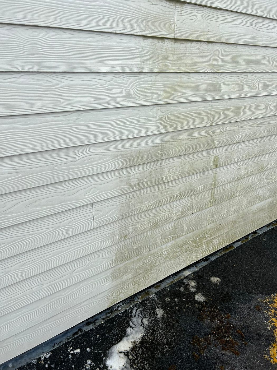 White weatherboard cladding soft washed to clear algae streaks on a home